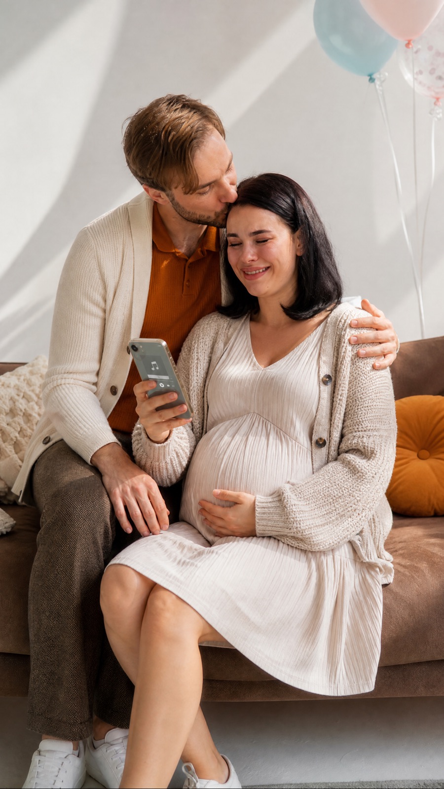 A pregnant woman and her partner on a sofa at their baby shower, crying at a lullaby for their son